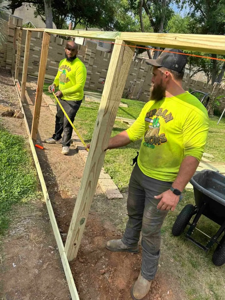 Two workers building a wooden structure outdoors.